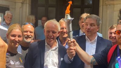 Vertreter der Stadt Oldenburg, der Gemeinde Hatten und der Gesetzlichen Unfallversicherung halten die Special Olympics Flamme vor dem Alten Rathaus