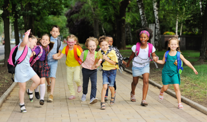 Schulkinder freudig in einer Reihe draußen zur Schule laufend