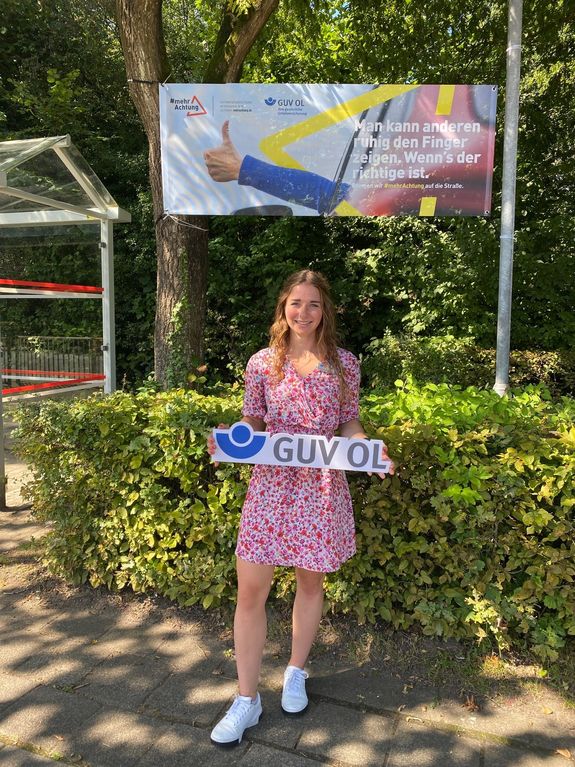 Präventionsberaterin des GUV OL, Theresa Wieting, präsentiert das aufgehängte Banner
