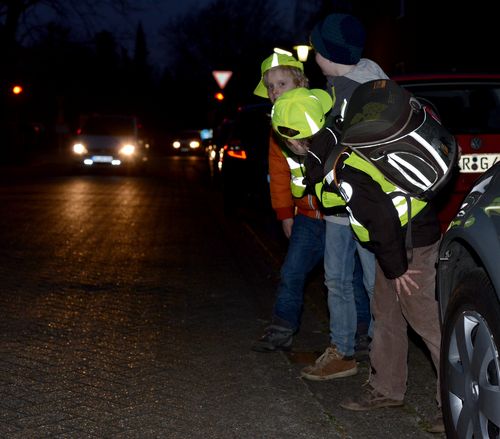 Dunkle Straße mit Kindern, die reflektierende Kleidung tragen