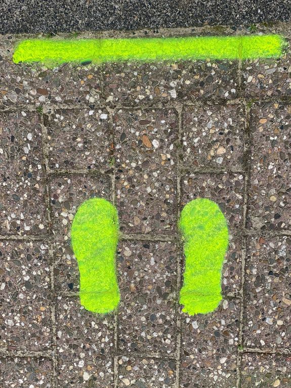 Auf den Bürgersteig aufgesprühte Fußabdrücke in neon gelb