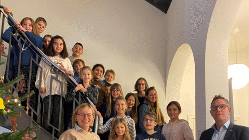 Viertklässlerinnen und Viertklässler stehen auf der Treppe mit dem GUV OL - Schild in der Hand zusammen mit ihrer Lehrerin Christine Krüger und Angela Pauka und Henning Wolff vom GUV OL 