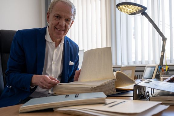 Michael May, Geschäftsführer des GUV OL, am Schreibtisch sitzend, lächelnd, im blauen Anzug mit weißem Hemd