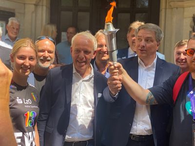 Vertreter der Stadt Oldenburg, der Gemeinde Hatten und der Gesetzlichen Unfallversicherung halten die Special Olympics Flamme vor dem Alten Rathaus