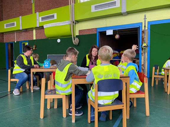Vorschulkinder beschäftigen sich mit Unfallprävention, malen sich mit Sicherheitsweste