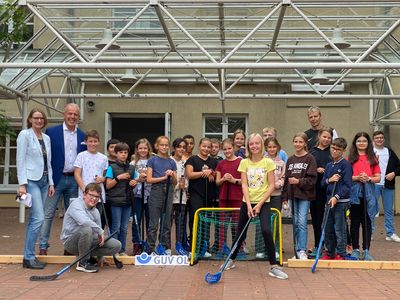 Gruppenfoto der Schülerinnen und Schüler des CAG zusammen mit der Schulleitung, dem Sportverantwortlichem und dem Vertreter des GUV OL vor dem Hockeytor im Pausenhof