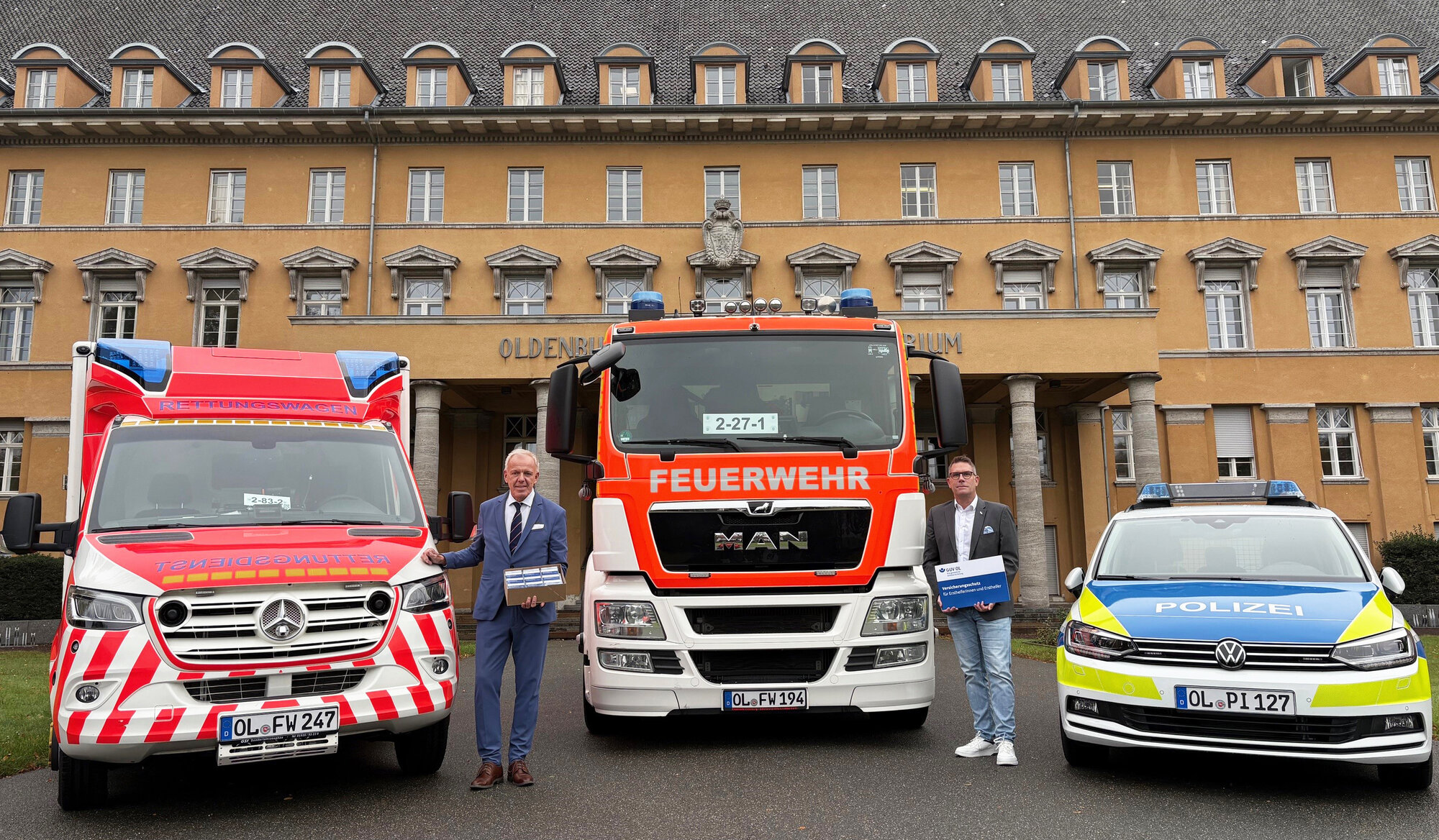 Vor den Einsatzfahrzeugen von Polizei, Feuerwehr und Rettungsdienst präsentieren Geschäftsführer des GUV OL, Michael May, und Henning Wolff, stv. Geschäftsführer, die Karte für Ersthelfende