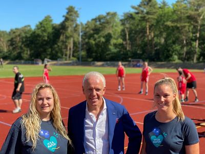 Auf dem Sportplatz in Hatten freuen sich die Koordinatorinnen des Host Town Programs Samantha Westphal, Stadt Oldenburg und Leonie Schulte, Gemeinde Hatten, über den Besuch von Michael May, Geschäftsführer des GUV OL